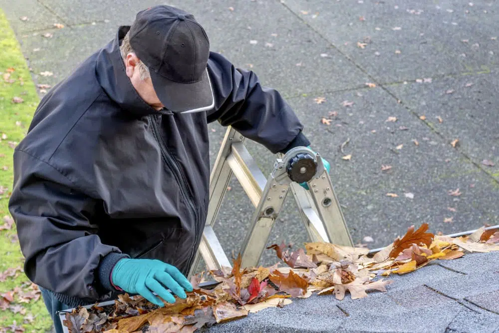 Personne entrain de nettoyer les gouttières